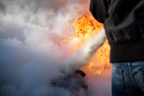 homme de derrière est la lutte contre un incendie avec de la mousse d’un extincteur, espace copie dans la fumée - formation incendie photos et images de collection